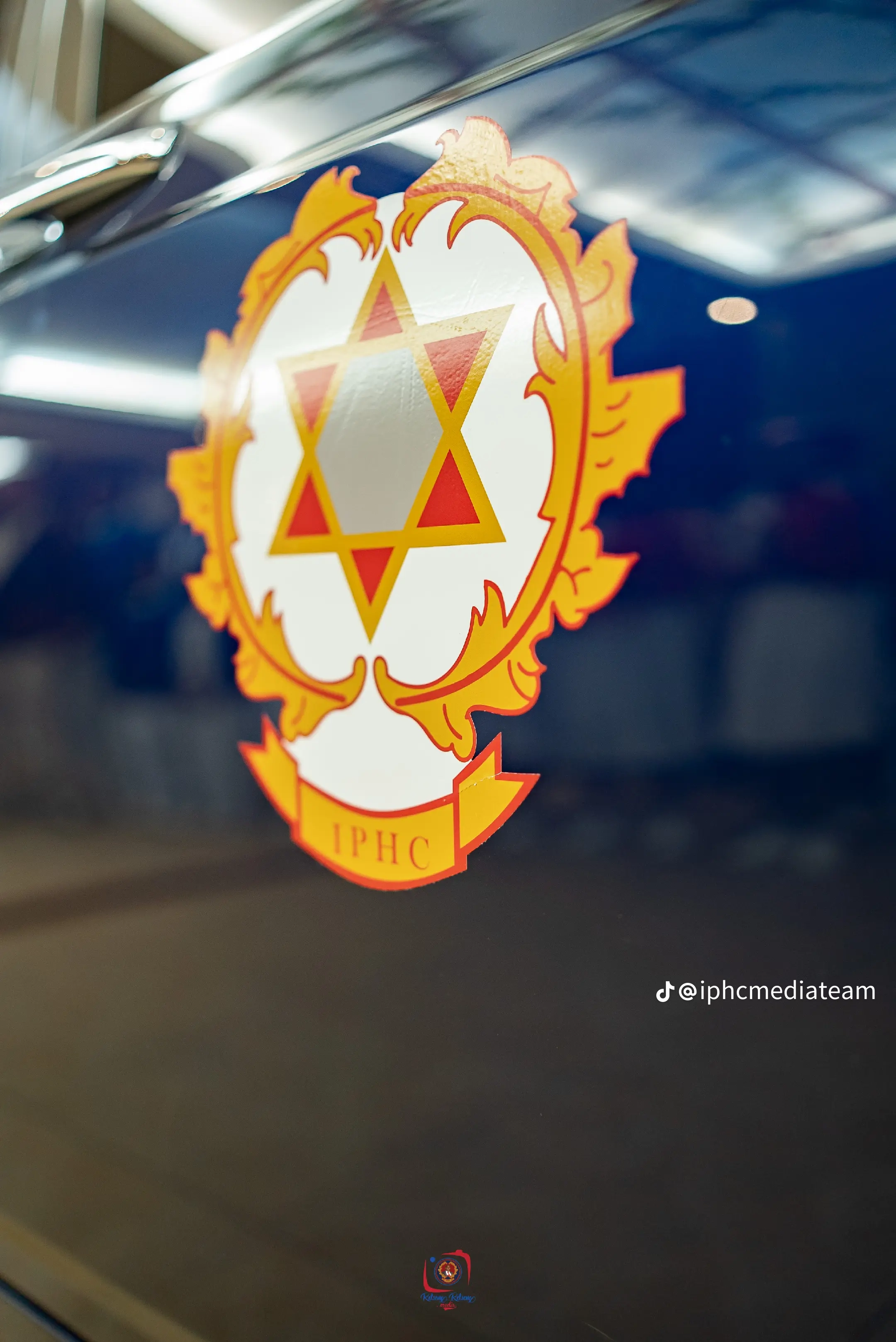 Close-up of the gold, red and white IPHC crest on dark blue bodywork