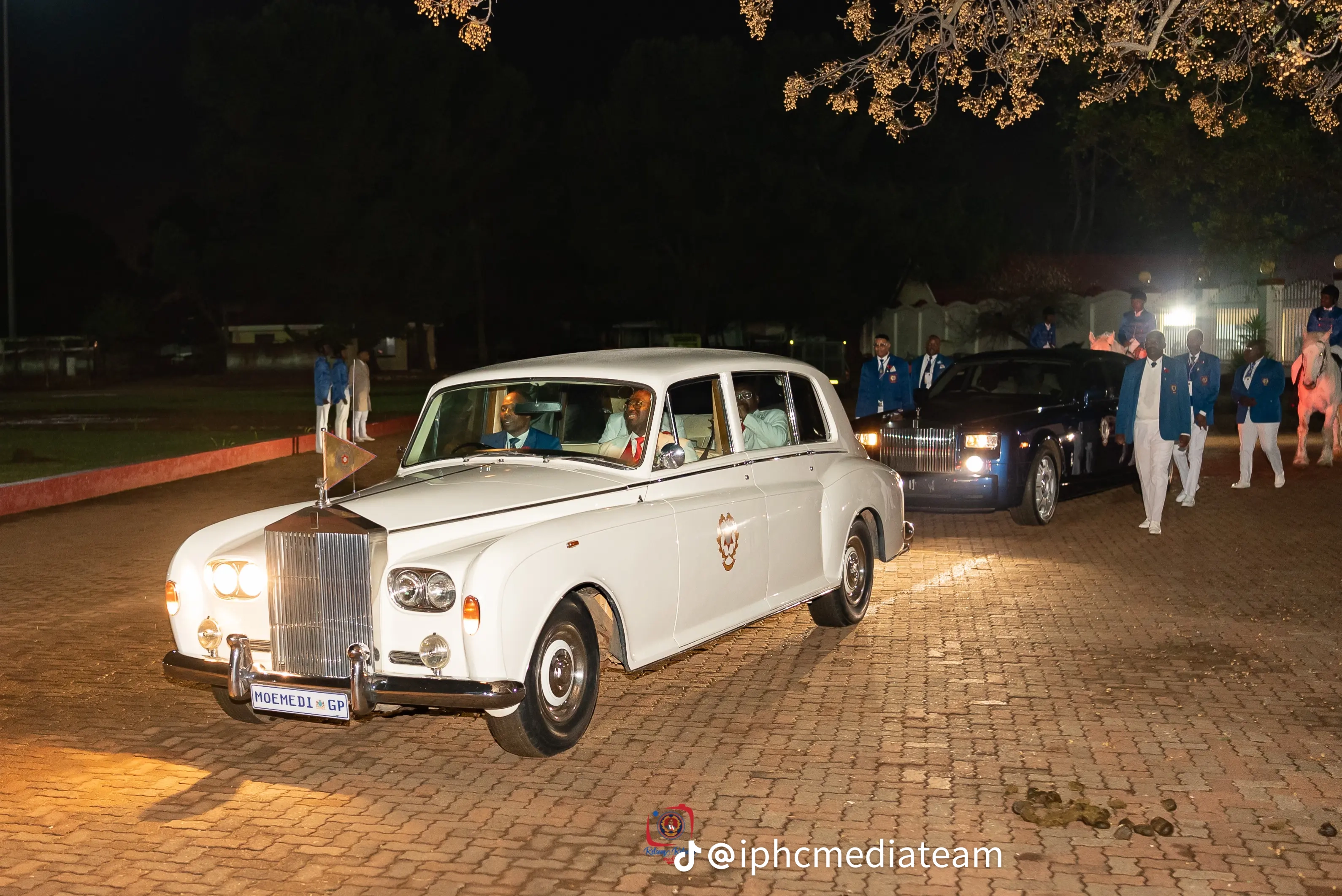 White IPHC vehicle leading a night-time procession